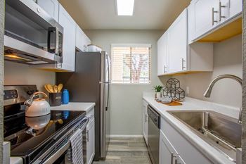 a small kitchen with white cabinets and stainless steel appliances at The Vintage Apartments, South Carolina, 85710